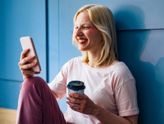 Mujer con teléfono móvil y café en la mano