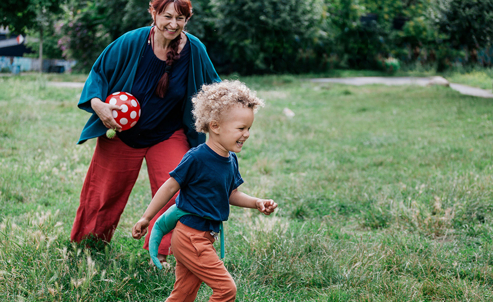 A woman and child playing ball outdoors. 