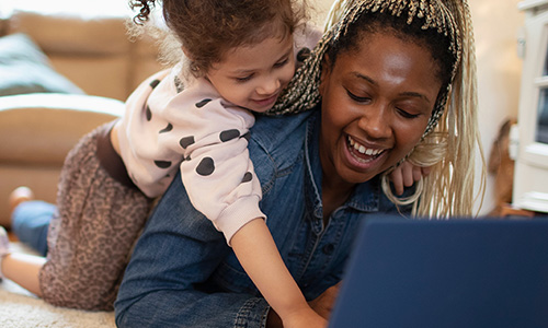 Mother reading Open Enrollment tips on the laptop with a happy child.