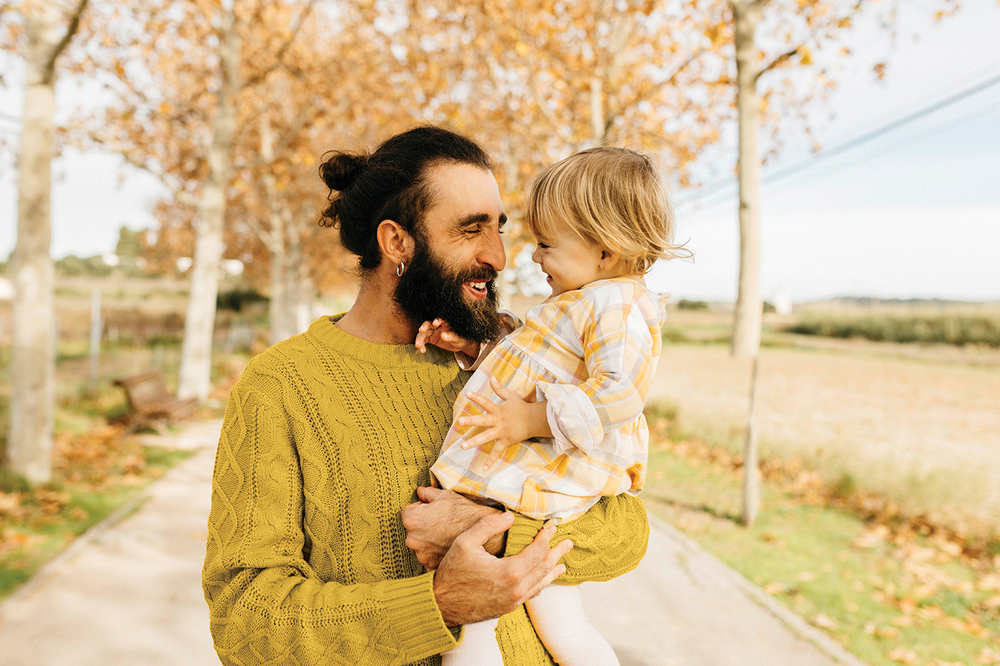 Father holding young daughter and laughing in the fall.