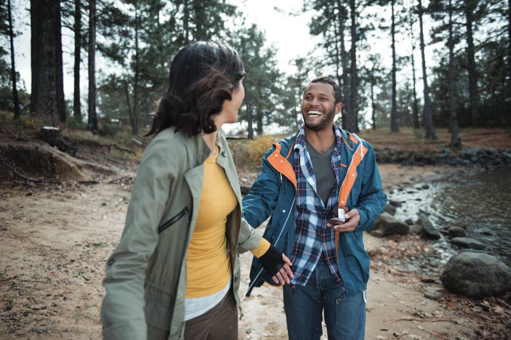 Man and woman hiking in a forest with gear they bought with Blue365 discounts.