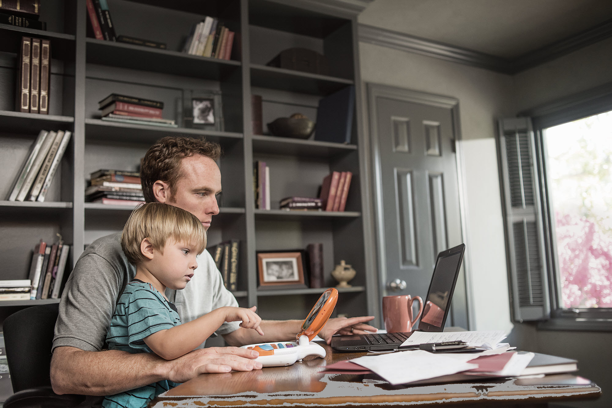 Man on computer holding a baby