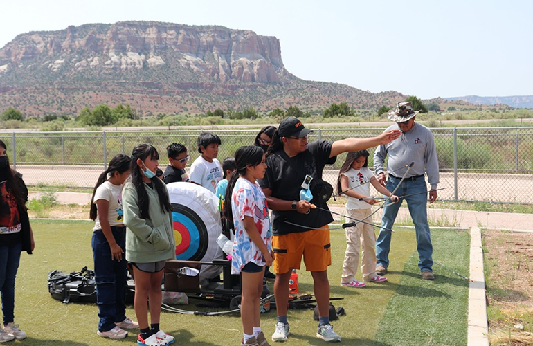 A group of Native American children practice archery